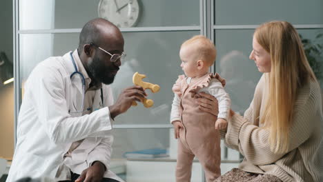 Pediatrician-Playing-with-Baby-Girl-and-Talking-to-Mother-in-Clinic
